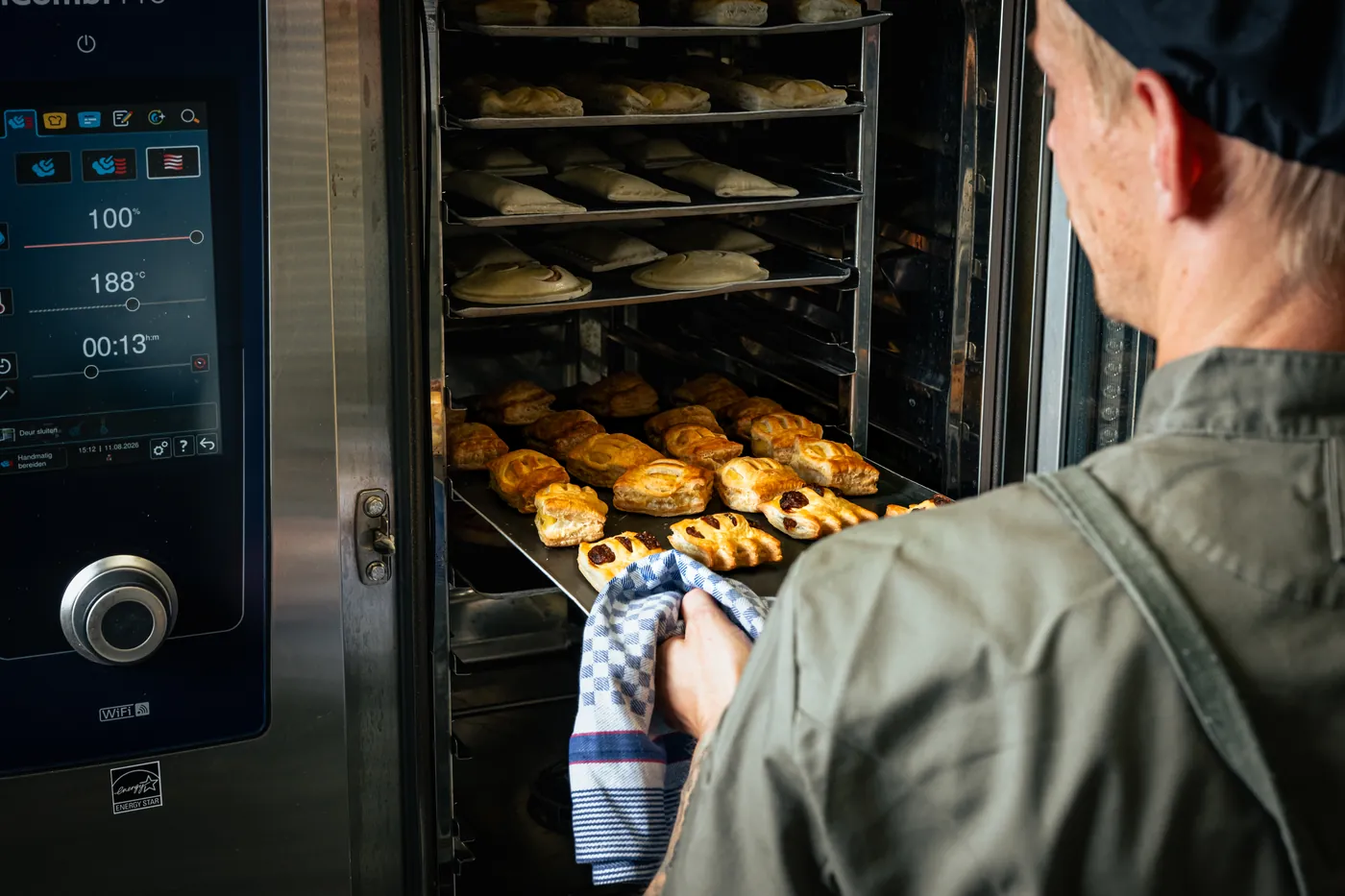 Chef haalt versgebakken hartige mini-broodjes uit de combi-oven